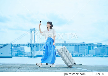 手裡提著手提箱行走的年輕女子 115509183