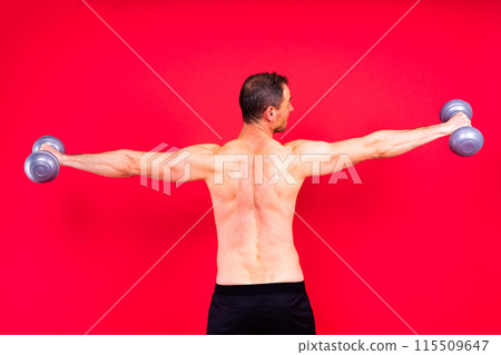 Adult muscular man smiling and screaming while working out hard with dumbbells. 115509647