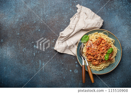 Plate of spaghetti bolognese with basil on dark background with space for text 115510908