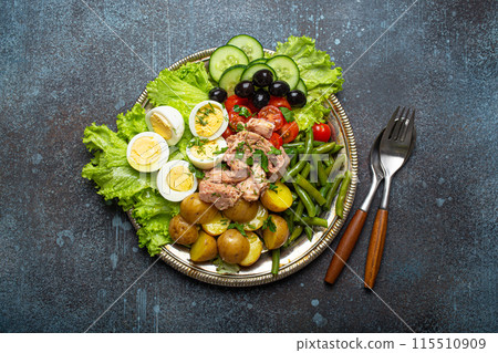 Nicoise salad with tuna, olives, green beans, tomatoes and quail eggs on a bed of lettuce 115510909