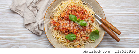 Plate of spaghetti bolognese with basil on wooden table Plate of spaghetti bolognese with basil on wooden table 115510936