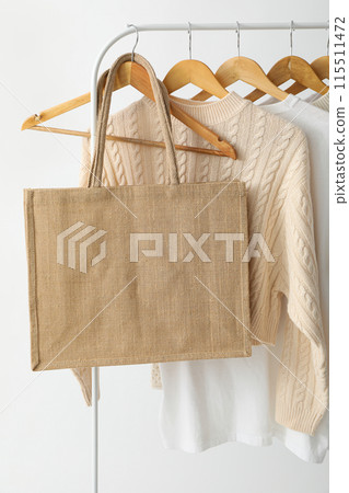 A bag hangs on a hanger with clothes 115511472