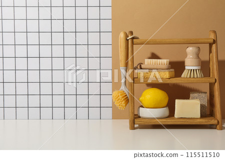 Brushes, sponge, soap and lemon on wooden shelf on light background, space for text 115511510