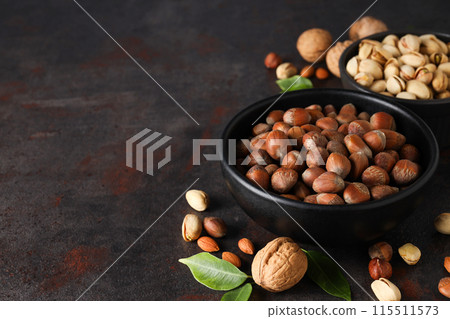 Different types of nuts in black bowls on a dark background 115511573