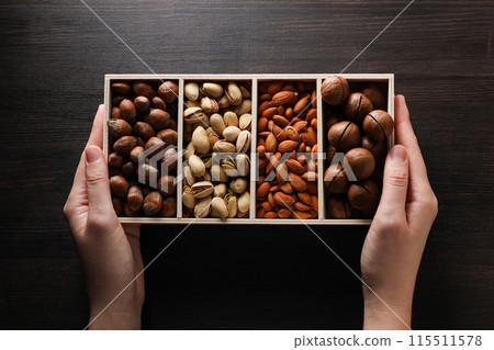 Wooden box with different nuts on a dark background Wooden box with different nuts on a dark background 115511578