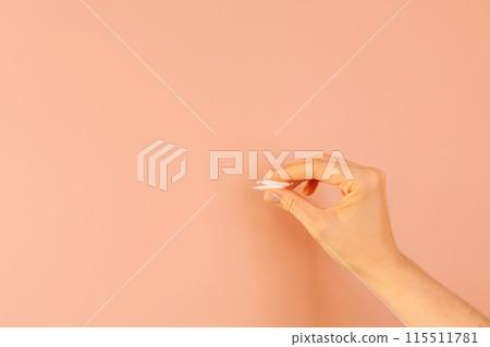 Hand holding white snus bags against brown background 115511781