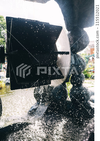 Water wheel in the park. A mechanism with a rotating motion that converts water energy into energy. Hydropower and kinetic generator 115512021