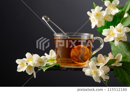 Cup of jasmine tea and fresh jasmine flowers on a black background. 115512180