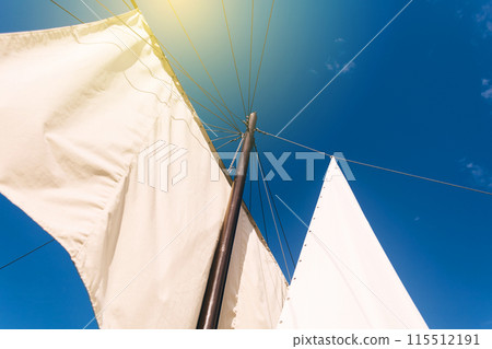 White sails close-up on a background of blue sky with clouds. Yachting and sailing. Summer vacation and travel at sea 115512191