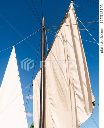 White sails close-up on a background of blue sky with clouds. Yachting and sailing. Summer vacation and travel at sea 115512193