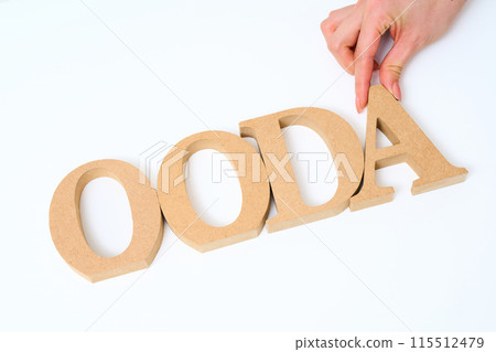 Wooden alphabet blocks arranged with the word "OODA" 115512479