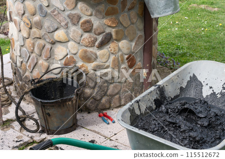 Silt from the bottom of a well in a bucket and a wheelbarrow. 115512672