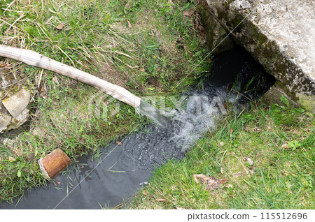 Water flows into the ditch from a hose. Water flows into the ditch from a hose. 115512696