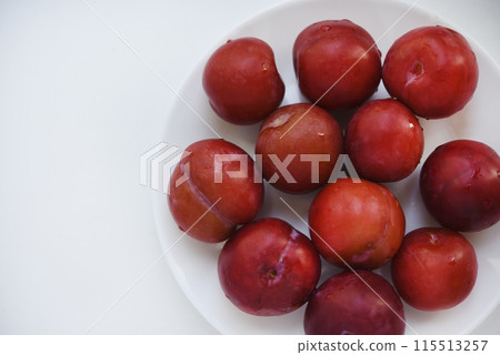 Red plums on a white background.  Plums on a plate. Washed fruits. 115513257