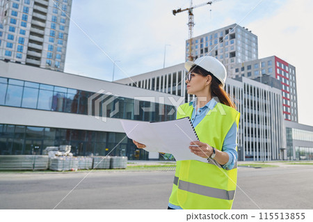 Industrial worker female builder with working documents, outdoor construction Industrial worker female builder with working documents, outdoor construction 115513855