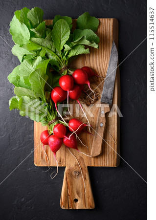 Wooden cutting board with two bunch of fresh red organic radish 115514637