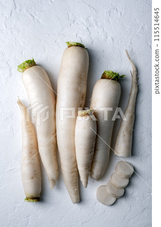 Whole and chopped white daikon radish roots on white background 115514645