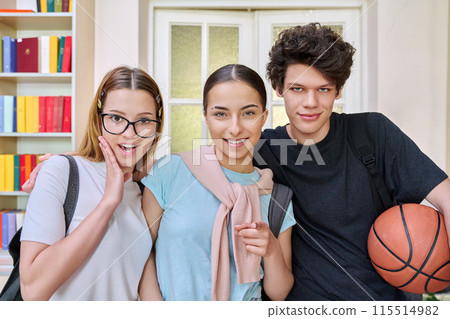 Three cheerful teenagers students looking at camera inside school campus 115514982