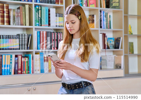 Teenage female student using smartphone, inside high school library 115514990