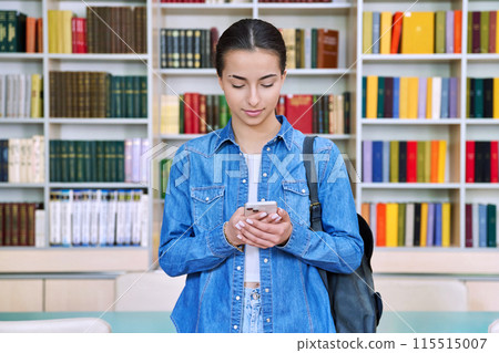 Teenage female student using smartphone, inside high school building, in library Teenage female student using smartphone, inside high school building, in library 115515007
