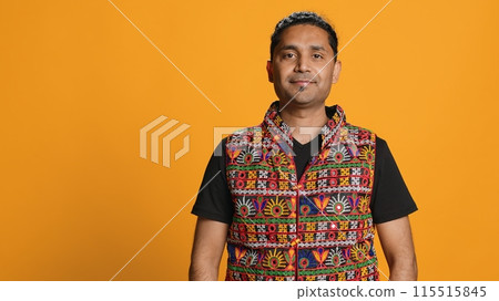 Portrait of optimistic indian man wearing colorful vest with positive facial expression smiling, looking pleased. Calm person in traditional clothing, feeling satisfied, studio backdrop, camera A Portrait of optimistic indian man wearing colorful vest with positive facial expression smiling, looking pleased. Calm person in traditional clothing, feeling satisfied, studio backdrop, camera A 115515845