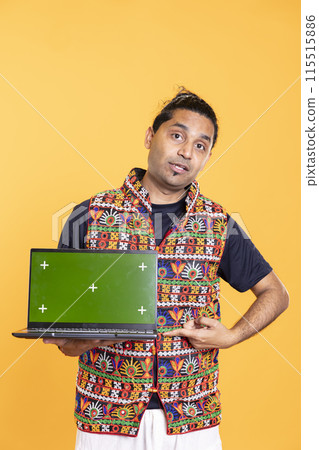Portrait of tech professional pointing finger towards green screen laptop, isolated over studio backdrop. Content creator doing technology reviews, presenting mockup notebook Portrait of tech professional pointing finger towards green screen laptop, isolated over studio backdrop. Content creator doing technology reviews, presenting mockup notebook 115515886