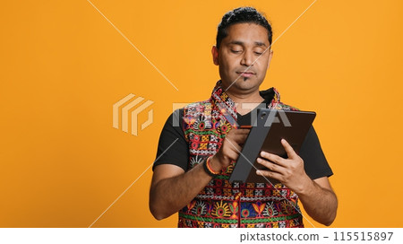 Man upset after lacking necessary money while trying to buy stuff online on tablet. Sad person looking at debit card after getting transaction rejected on device, studio background, camera A 115515897