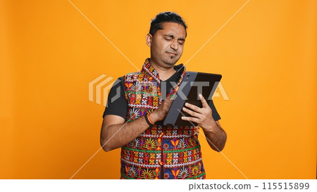 Man upset after lacking necessary money while trying to buy stuff online on tablet. Sad person looking at debit card after getting transaction rejected on device, studio background, camera B Man upset after lacking necessary money while trying to buy stuff online on tablet. Sad person looking at debit card after getting transaction rejected on device, studio background, camera B 115515899