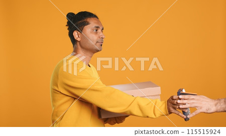 Indian delivery worker offering takeaway order to customer paying with debit card. Client buying meal from courier, swiping card on POS device, studio background, camera A Indian delivery worker offering takeaway order to customer paying with debit card. Client buying meal from courier, swiping card on POS device, studio background, camera A 115515924