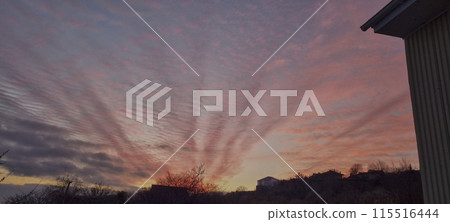 Beautiful crimson sunset.The rays of the sun highlight the elongated clouds with their rays Beautiful crimson sunset.The rays of the sun highlight the elongated clouds with their rays 115516444