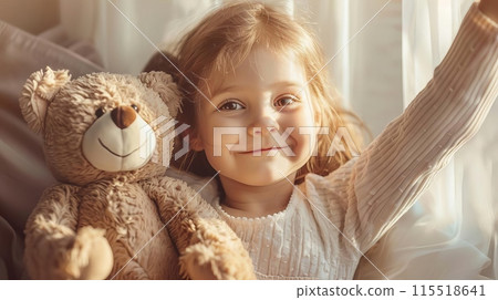 Happy little girl with teddy bear in cozy room, smiling and waving in warm natural light, creating a heartwarming moment of childhood joy. Happy little girl with teddy bear in cozy room, smiling and waving in warm natural light, creating a heartwarming moment of childhood joy. 115518641