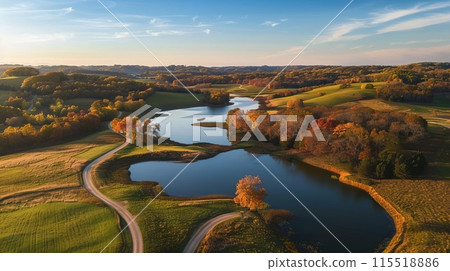 Aerial view of a winding river surrounded by autumn trees and rolling hills under a blue sky at sunset. Aerial view of a winding river surrounded by autumn trees and rolling hills under a blue sky at sunset. 115518886