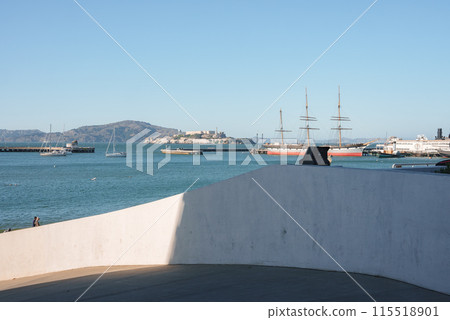 Serene waterfront view in San Francisco with boats and historical sailing ship, hilly landscape, blue sky. Possibly near Pier 39, not showing Golden Gate Bridge. Serene waterfront view in San Francisco with boats and historical sailing ship, hilly landscape, blue sky. Possibly near Pier 39, not showing Golden Gate Bridge. 115518901