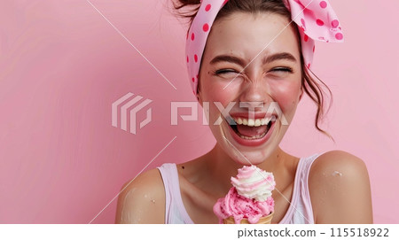 Cheerful young woman with a pink polka-dot headband laughing and enjoying a pink and white ice cream cone against a pink background. 115518922