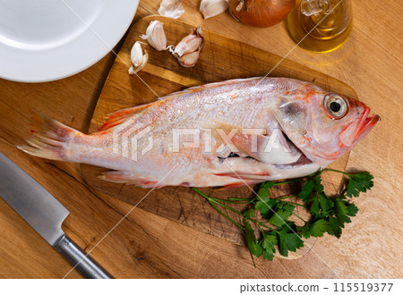 Raw whole red palometa fish with garlic and parsley on desk 115519377