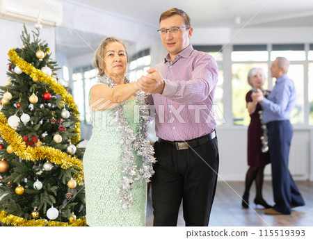 Middle-aged man engaged in dance hall with mature female partner and dances Latin rumba during celebration Christmas. Hobby, healthy lifestyle concept 115519393