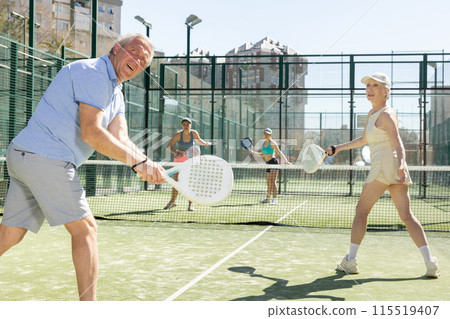 Mature sporty mature couple playing padel game in court on sunny day 115519407
