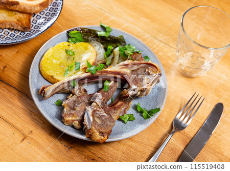 Lamb ribs served with potatoes and peppers 115519408