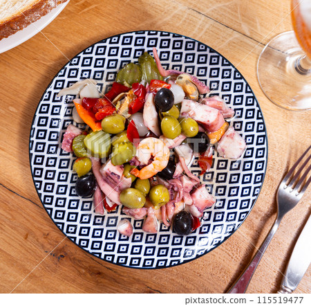 There is portion of seafood tapas salpicon with green and black olives on plate 115519477