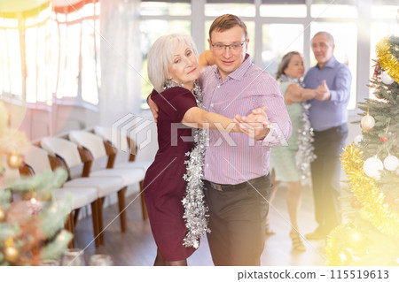 Middle-aged man and elderly woman dancing contemporary discofox in couple in New Year atmosphere 115519613