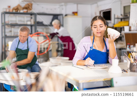 woman paints vase that she made herself 115519661