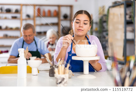 Woman is learning to paint on ceramic cup in handicraft workshop, handmade art and hobby concept 115519772