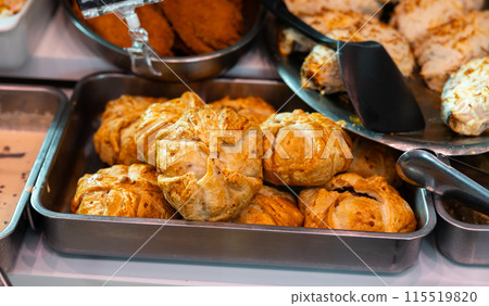 Golden baked empanadas on metal tray on display in local deli 115519820