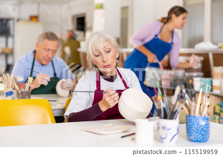Mature woman painting clay ceramic at art studio 115519959