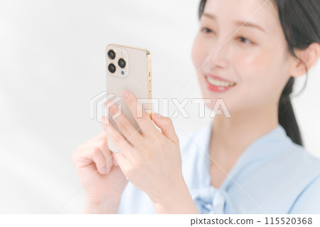 A smiling woman holding a smartphone 115520368