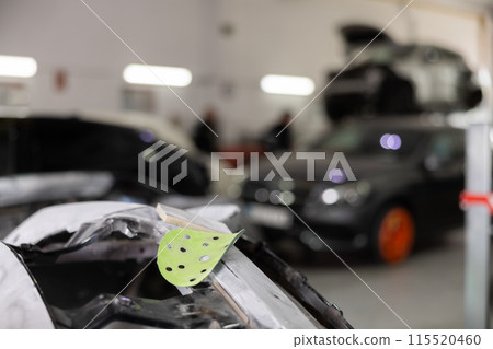 Various parts of car on stands for painting. Garage painting car service. Repairing car body work after accident by working sanding primer before painting 115520460