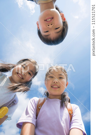 Smiling elementary school student (child) peering into the camera at the blue sky Smiling elementary school student (child) peering into the camera at the blue sky 115521701