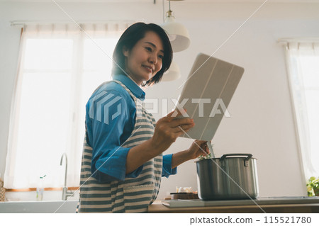 Middle-aged woman looking at a tablet in the kitchen 115521780