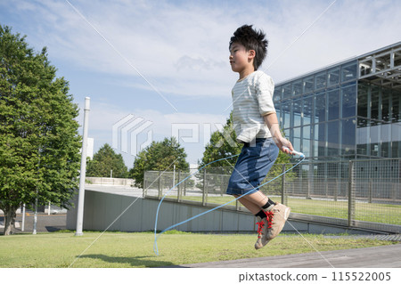 A male elementary school student jumping rope in a schoolyard 115522005