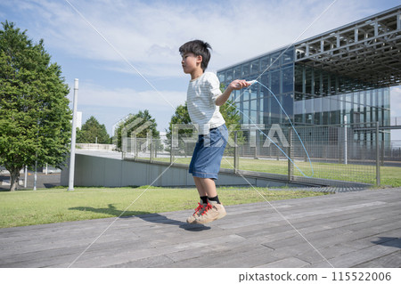 A male elementary school student jumping rope in a schoolyard 115522006